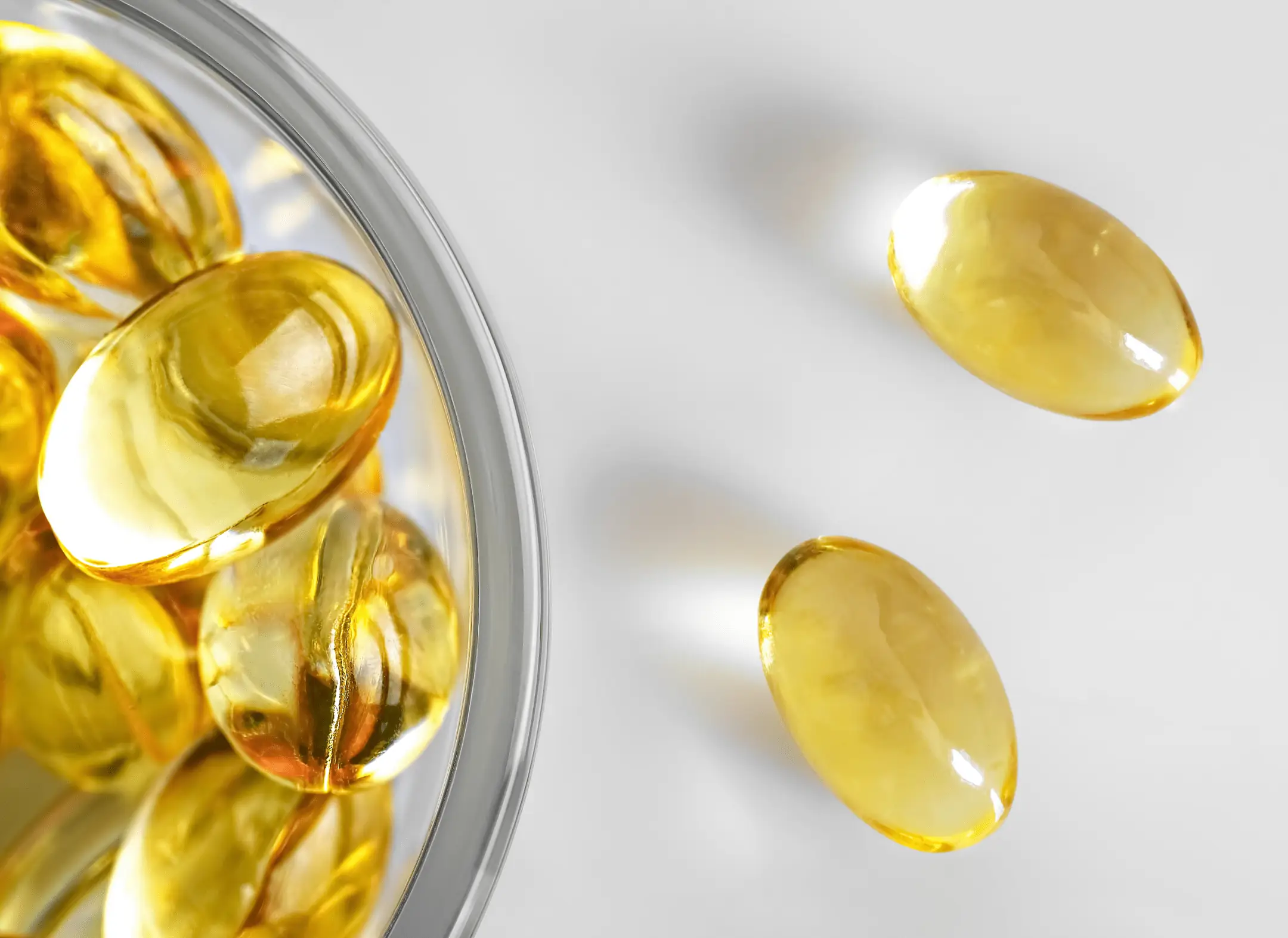 Golden vitamin E softgels in a glass dish